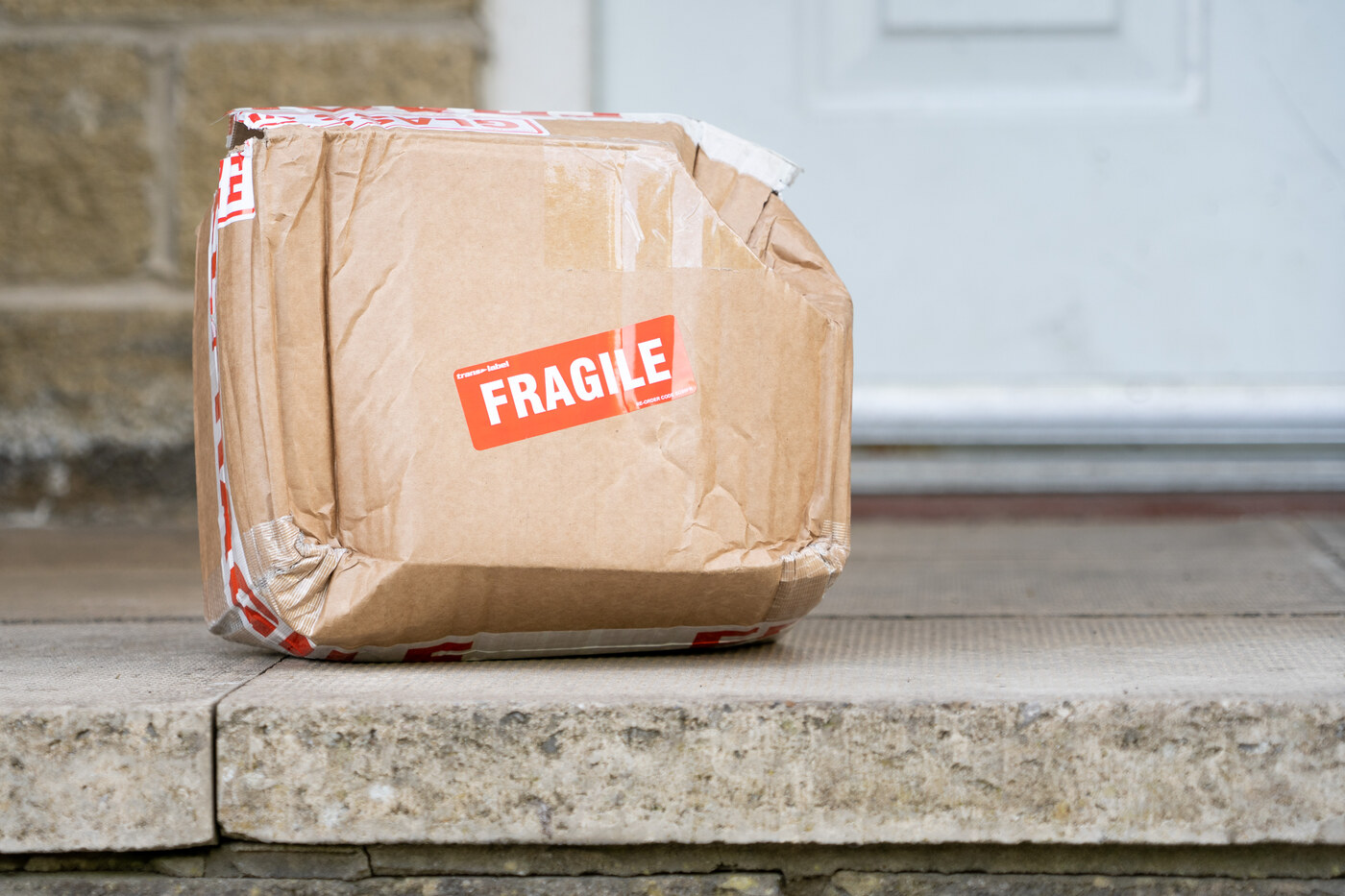 Crushed fragile parcel at a doorstep — should fail the package condition check.